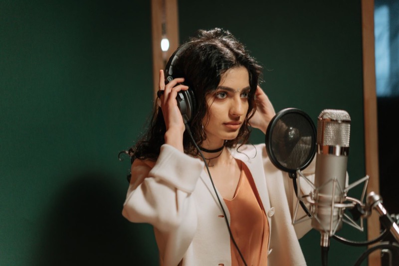 Cantora com fone de ouvido em frente ao microfone de estúdio